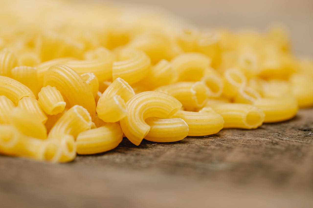 contact-img Closeup of pile of fresh uncooked curvi rigati pasta scattered on wooden table in kitchen