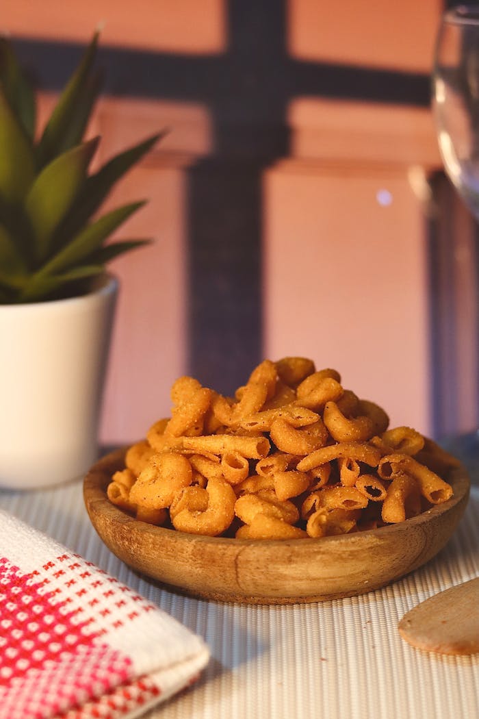 Close-up of spicy pasta snack in a wooden bowl, set on a cozy evening tabletop.